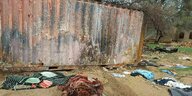Vor einer Mauer liegen getötete Einwohner von Geneina, die mit Decken abgedeckt sind