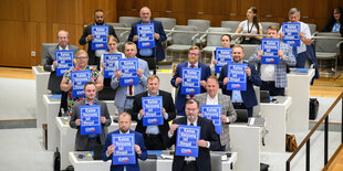 AfD-Abgeordnete halten Schilder mit der Aufschrift "Keine Heizung ist illegal" hoch