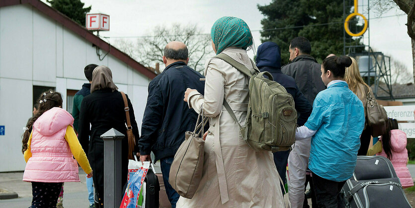 Menschen mit Gepäck gehen in das Grenzdurchgangslager Friedland