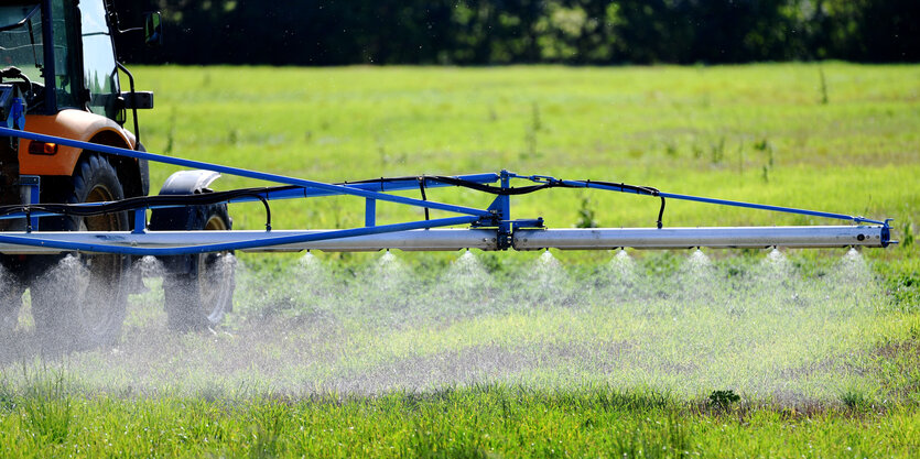 Ein Traktor mit Spritzmaschine sprüht Glyphosat auf dem Feld aus