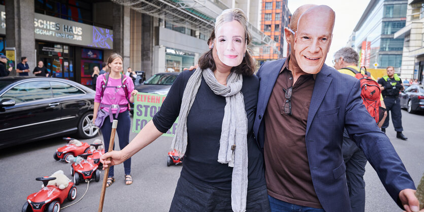 Zwei Menschen auf der Friedrichstraße mit Manja-Schreiner- und Kai-Wegner-Maske