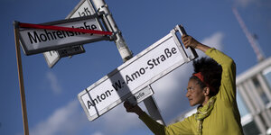 Eine Schwarze Aktivistin ersetzt das Straßenschild Mohrenstraße durch ein neues mit der Aufschrift Anton-Wilhelm-Amo-Straße.