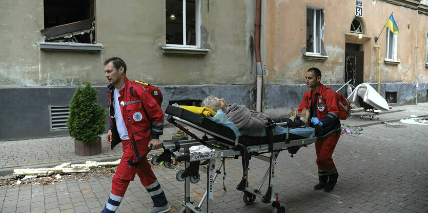 Zwei Sanitäter transportieren eine Person auf einer Liege