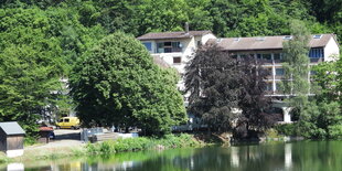 Gebäude im Grünen, im Vordergrund eine Wasserfläche