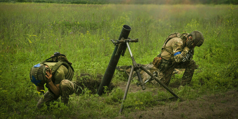 Zwei ukrainische Soldaten halten sich die Ohren zu, nachdem sie eine Granate abgefeuert haben