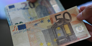 Ein 50 Euro Geldschein wird ins Bild gehalten, dahinter ist ein 20 Euro Schein zu sehen.