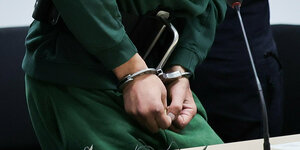 Die mit Handschellen gefesselten Hände des Angeklagten, der einen grünen Anzug trägt