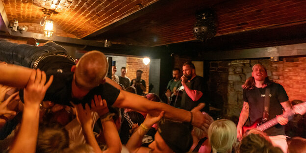 Ein Stagediver in Publikumsmasse vor der Band im Keller