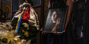 Ein Portrait von Victoria Amelina vor einem Sarg