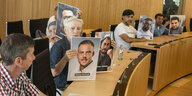 Freunde und Angehörige nehmen an der Sitzung in Wiesbaden teil und halten Fotos der Ermordeten in die Kamera