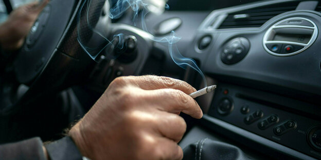 Ein Mann im Auto hält eine brennende Zigarette in der Hand