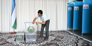 Ein Mann begutachtet die durchsichtigen Wahlurnen in einem Wahllokal