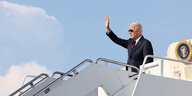 Joe Biden steht mit Sonnenbrille auf einer Gangway und winkt