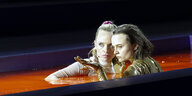 Zwei Frauen nah beieinander in einem Becken mit orangeroter Flüssigkeit