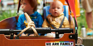Der Kinderwagen einer Regenbogenfamilie (zweier Väter) mit zwei Kindern und einem bekennenden Aufkleber.