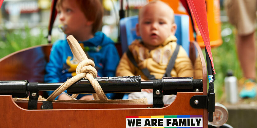 Der Kinderwagen einer Regenbogenfamilie (zweier Väter) mit zwei Kindern und einem bekennenden Aufkleber.