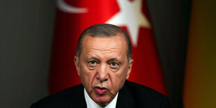 Erdogan spricht und sitzt vor einer Flagge der Türkei