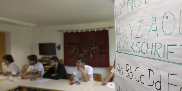 Flüchtlinge sitzen gemeinsam in einem Raum und erhalten Deutschunterricht