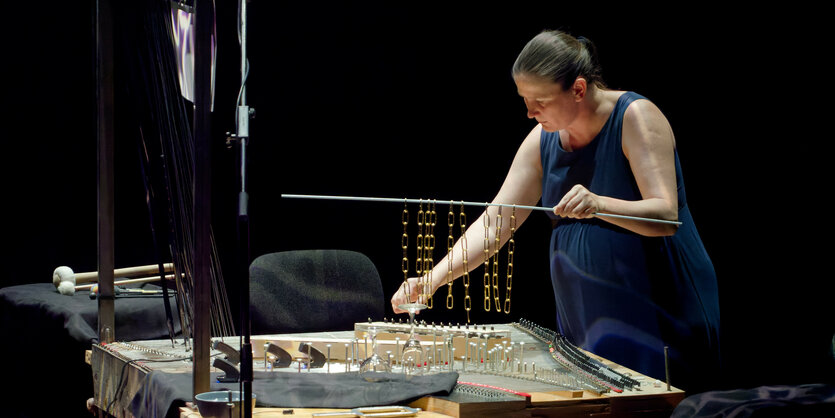 Eine Frau steht an einem selbstgebauten Instrument