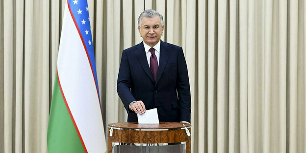 Schawkat Mirzijojew, Präsident von Usbekistan, gibt in einem Wahllokal seinen Stimmzettel ab und schaut staatstragend in die Kamera