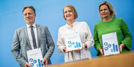 Nancy Faeser, Lisa Paus und Holger Münch stehen mit der Broschüre zu "häuslicher Gewalt" vor einer blauen Wand