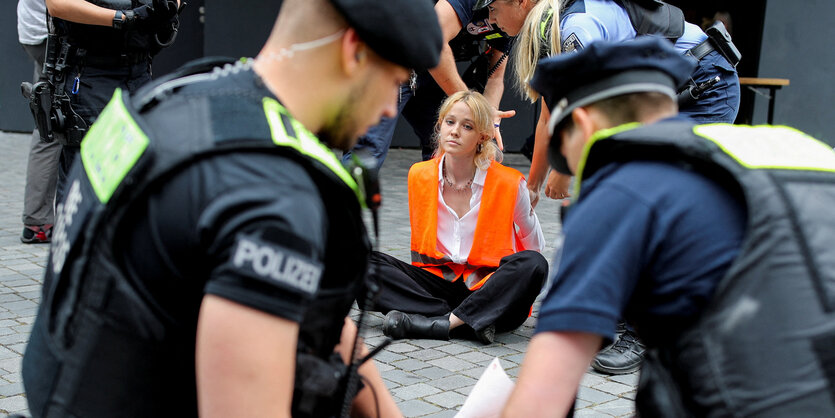 Polizistien umringen eine Blockiererin der Letzten Generation