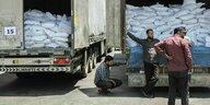 Syrer inspizieren Lastwagen, die mit weißen Säcken beladen sind