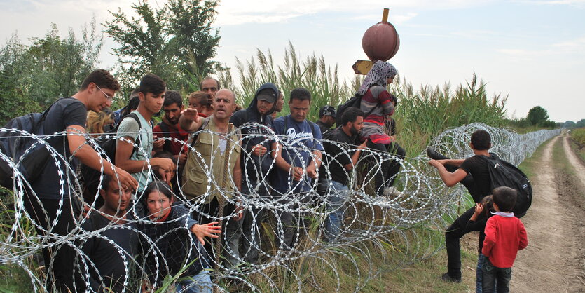 Syrische Flüchtlinge an Grenzzaun mit Stacheldraht