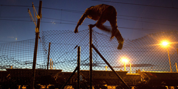 Mann, der nachts über einen Zaun klettert