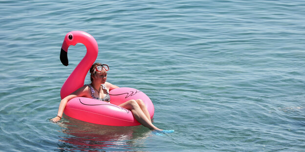 Ein Kind in einem aufblasbaren Flamingo im Wasser