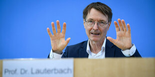 Karl Lauterbach hebt auf der Pressekonferenz die Hände