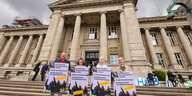 Vier Aktivist*innen der Initiative Expedition Grundeinkommen stehen vor dem hanseatischen Oberlandesgericht. Sie halten Plakate in den Händen.