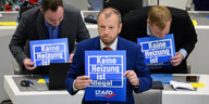 Stefan Marzischewski-Drewes und weitere Fraktionsmitglieder der AfD halten im niedersächsischen Landtag während der Debatte Schilder mit Aufschrift „Keine Heizung ist illegal“.