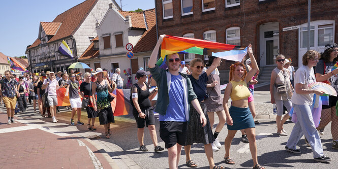 Menschen mit Regenbogenfahnen in einer kleinen stadt