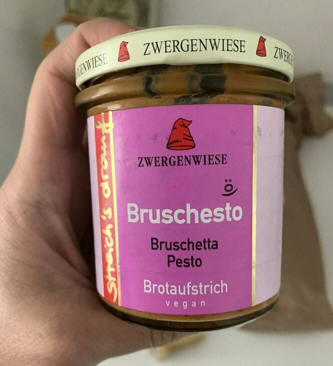 Eine Hand hält ein Glas Zwergenwiese streich's drauf Bruschesto Bruschetta Pesto