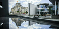 Das Reichstagsgebäude (l) spiegelt sich neben dem Paul-Löbe-Haus (r) des Deutschen Bundestages in einer Glasfläche.