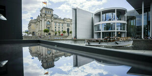 Das Reichstagsgebäude (l) spiegelt sich neben dem Paul-Löbe-Haus (r) des Deutschen Bundestages in einer Glasfläche.