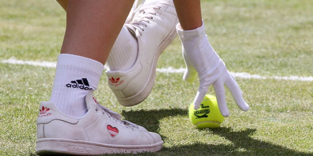 Ein Tennisball in Großaufnamne und eine Hand: Nur mit Handschuhen dürfen die Tennisbälle von Ballmädchen und Balljungen angefaßt werden