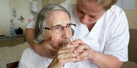 Einr Pflegerin hilft einer älteren Person beim Trinken.