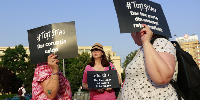 Protestierende halten schwarze Schilder mit weißer Schrift hoch