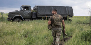 Soldat mit Waffe läuft zu einem Lkw.