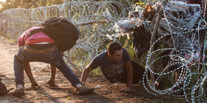 Flüchtlinge klettern durch den Zaun an der ungarisch-serbischen Grenze.