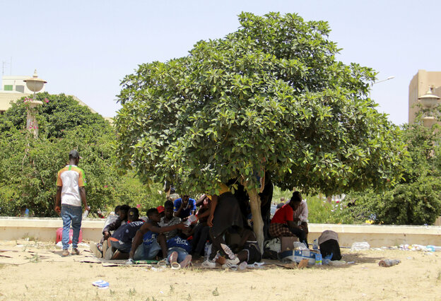 Migrant:innen suchen unter einem Baum Schatten