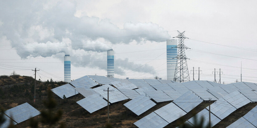 rauchende Schornsteine, im Vordergrund Solar Paneele