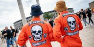 Im Hintergrund ist das Berliner Olympiastadion zu sehen. Im Vordergrund sehen wir die Rücken von zwei Männern in orangefarbenen Overalls, darauf jeweils ein Totenkopf und die Aufschrift: "Rammstein, Deutschland, 1994"