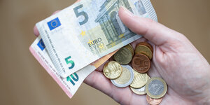 Person hält Euroscheine und Münzen in der Hand