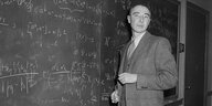 Robert Oppenheimer steht an einer Tafel mit Formeln und Berechnungen.