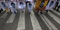 Menschen mit Plakaten in den Händen, auf denen die Gesichter der Verschwundenen abgebildet sind