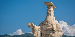 Konfuzius Statue aus Stein vor Bergen und Wolken