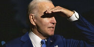 Joe Biden schützt seine Augen mit der Hand vor dem Sonnenlicht.
